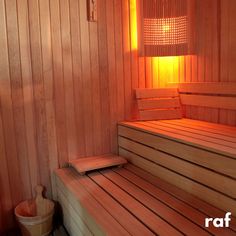 a sauna with wooden benches and lights in the corner, next to a basket