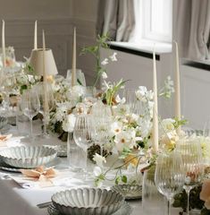 the table is set with white flowers, candles and glassware for dinner guests to enjoy