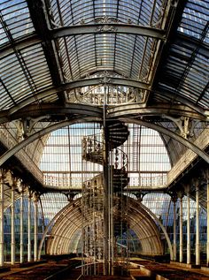 the inside of a train station with lots of glass and metalwork on it's ceiling