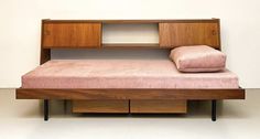 a bed with a wooden headboard and pink bedspread on top of it