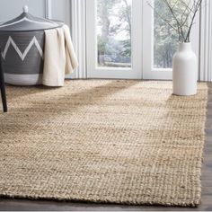 an area rug in front of a door with a vase on the floor next to it