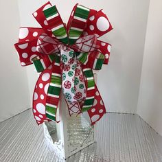 a red and green bow with white polka dots on the top is sitting in a clear container