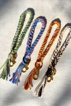 four different colored bracelets with tassels and bells on white fabric background, closeup