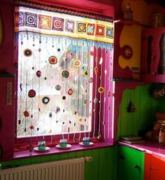 a kitchen with green and pink walls and colorful curtains