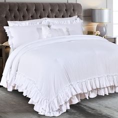 a bed with white sheets and ruffles on it