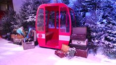 a red trolley car sitting in the middle of a snow covered forest