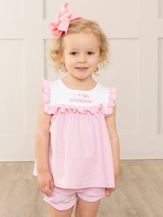 Bask in the sunny warmth of familial bonds with our latest exclusive MNC Basics collection: Family Love. Our soft, comfortable, high quality fabric is back in soft stripes, dainty florals, and ruffles galore. With embroidered messaging expressing love to the family, your little ones will love these spring basics! Show off your little one's love for her grandma in our Pink Grandma Love Ruffle Outfit! This girls' ruffle short set features charming pink and white stripes, accented with an embroidered "I 🩷 My Grandma". The perfect outfit for family gatherings or just hanging out with grandma. So cute, grandma will surely approve!   Fits true to size. Top: 95% Cotton / 5% Spandex Bottom: 95% Cotton / 5% Spandex  Suggested bow color : #1 and #31 Accessories sold separately. Import.  Adalyn is 3 Sweet Cotton Sets With Ruffles, Sweet White Sets With Ruffles, Spring Sleepwear With Ruffles, Cute Striped Cotton Sets, Cute Ruffled Sleepwear For Spring, Spring Family Matching Pink Sets, Family Matching Pink Sets For Spring, Cute Cotton Daywear Sets, Cute Cotton Sets For Daywear