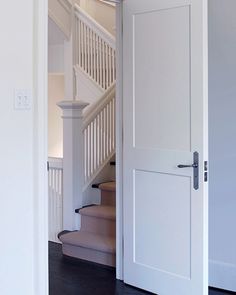 an open door leading to a stairway in a white house with wood floors and stairs