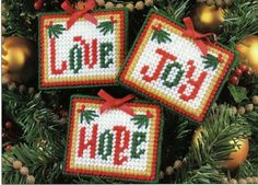 three cross stitch christmas ornaments hanging from a tree