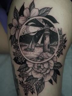 a woman's thigh with a lighthouse and flowers in the center on her leg