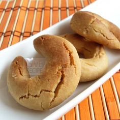 three cookies are on a white plate next to an orange place mat and woven table cloth