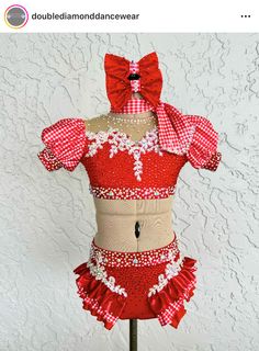 a red and white dress on a mannequin with a bow at the top