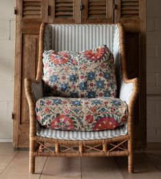 a chair that is sitting in front of a wooden wall with shutters on it