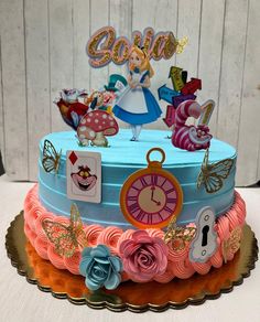 a birthday cake decorated with an alice in wonderland theme and lots of decorations on top