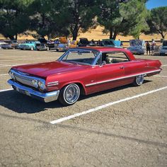 an old red car parked in a parking lot