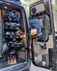 the back end of a van filled with luggage and backpacks, sitting next to another vehicle