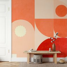 a living room with an orange and pink wallpaper, coffee table and vases