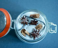 an open glass jar filled with cinnamons and star anise on a blue surface