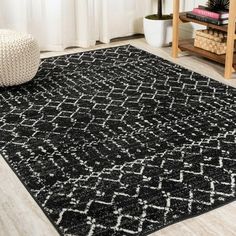 a black and white area rug in a living room with a plant on the floor