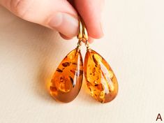 "Light orange natural amber earrings for women that love bright eye-catching colors. These drop shape genuine amber earrings brighten up your eyes. And we've heard - some lives too! Even though they are in cognac color, all they do is sweetens your life. MATERIALS AND SIZE: Stone: 100% Natural Baltic Amber Findings: Sterling silver 925 gold plated Earrings A: Weight: 7 g (0,324 oz) Bead size: 3 cm (1,18 in) x 1,6 cm (0,62 in) Total earring length:4,7 cm (1.85 in) Earrings B: Weight: 8,4 g (0,29o Hypoallergenic Amber Teardrop Jewelry, Amber Teardrop Earrings As A Gift, Amber Earrings For Gift, Amber Teardrop Earrings Gift, Amber Teardrop Drop Earrings For Gift, Baltic Amber Earrings As A Gift, Amber Teardrop Earrings, Baltic Amber Teardrop Earrings For Gift, Baltic Amber Teardrop Earrings As Gift