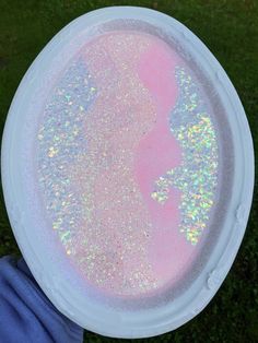 a white frisbee with pink and blue hologish on it in the grass