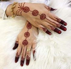 two hands with henna designs on them, one is red and the other is white