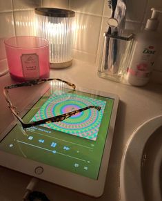 a tablet with glasses on top of it sitting on a counter next to a sink