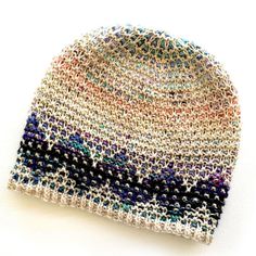 a multicolored knitted beanie sits on a white surface