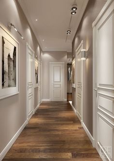 an image of a long hallway with white walls and wood flooring on one side