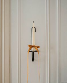 a candle is hanging on the wall with a bow around it's neck in front of a white door