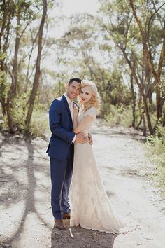 a bride and groom pose for a photo in the woods