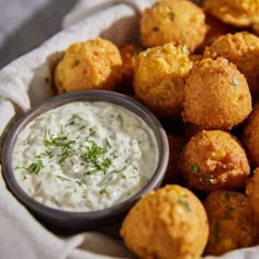 a basket filled with fried food next to a small bowl of ranch dip on the side