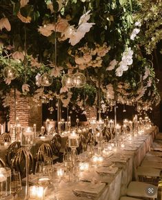 a long table is set with candles and flowers hanging from the ceiling, along with clear glass vases