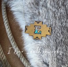 "Hand stamped and hand painted Leather necklace with the Letter E. Perfect to wear alone or layer with other necklaces! Leather pendant is 2 1/4\" wide by 1 3/4\" tall Approx. 16\" around" Southwestern Style Gold Necklace For Gift, Western Stamped Brown Jewelry, Western Style Stamped Brown Jewelry, Western Style Hand-tooled Jewelry Gift, Western Brown Stamped Jewelry, Handmade Western Style Necklace For Gift, Southwestern Style Hand Tooled Necklace As Gift, Handmade Western Style Necklace, Rustic Hand Painted Jewelry For Gifts