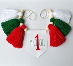 two tassels are attached to the neck of a red, green and white necklace