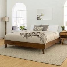 a bedroom with white brick walls and hardwood floors is pictured in this image, the bed has two nightstands on each side