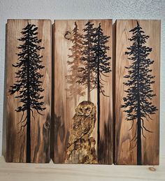 three wooden panels with trees and an owl on them