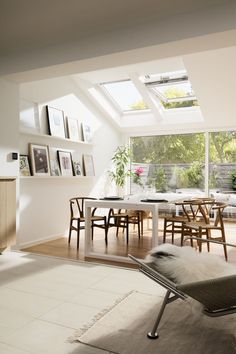 a living room filled with furniture and a skylight above the dining table, along with pictures on the wall