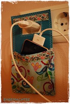 an electric outlet plugged into a phone in a purse on the wall next to a power strip