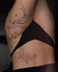 a woman's stomach with tattoos on the side and behind her is a black chair