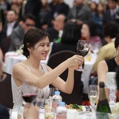 a woman sitting at a table holding a glass of wine