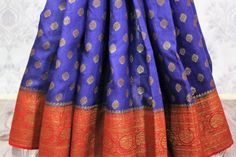 Traditional dark blue Muga Banarasi saree for weddings, parties and festive occasions! The antique zari work on the red border and pallu along with buta makes the saree absolutely rich. It comes with a matching red blouse piece. Buy this traditional saree online at Pure Elegance or visit our store in USA! Disclaimer: The actual product may vary slightly from the image. These are custom orders, hence expect slight variation in color, placement of the motif or buta. ESTIMATED DELIVERYBecause this is a custom order, it would take about 4 weeks from the date of purchase. RETURN POLICYThis product is a custom order and cannot be returned or exchanged. Transitional Blue Raw Silk Lehenga, Blue Chanderi Anarkali Set With Pallu, Blue Silk Anarkali Set With Pallu, Blue Meenakari Anarkali Set For Diwali, Blue Traditional Wear For Ceremonies In Transitional Season, Semi-stitched Blue Anarkali Set With Meenakari, Blue Semi-stitched Anarkali Set With Meenakari, Festive Blue Anarkali Set With Self Design, Blue Meenakari Anarkali Set For Festive Occasions