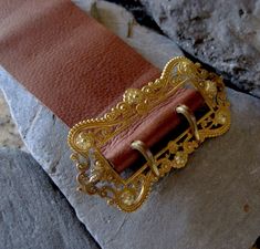 "This Victorian gold filled buckle has been sitting on my desk for 8 years. It is elegantly designed with a scroll and floral motif. I have wanted to make this into a bracelet but just couldn't find the time. I finally experimented with the leather. I chose a very supple leather that will probably darken from wearing and the oils in your skin giving it natural marks. For my first leather bracelet, I am happy with how it came out. The holes are not perfectly aligned but they look pretty good. Wha Elegant Brown Belt Buckles With Brass Hardware, Elegant Engraved Gold Belt Buckles, Formal Gold Engraved Belt Buckles, Elegant Gold Engraved Belt Buckles, Elegant Adjustable Belt Buckles With Brass Buckle, Elegant Adjustable Belt Buckle With Brass Detail, Adjustable Gold Belt Buckle As Gift, Luxury Adjustable Jewelry With Antique Buckle, Classic Formal Jewelry With Brass Hardware