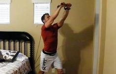 a man is doing exercises on the wall in his bedroom while holding onto an exercise rope