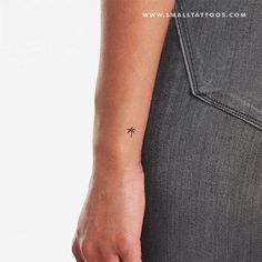 a small palm tree tattoo on the left side of her right arm, in front of a white background