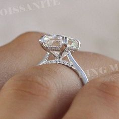 a close up of a person's hand with a diamond ring on their finger