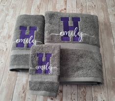 three gray towels with purple and white letters that spell out the word h on them