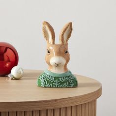 a rabbit figurine sitting on top of a wooden table next to christmas ornaments