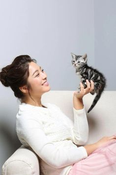 a woman sitting on a couch holding a kitten