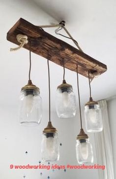 four mason jar lights hanging from a wood beam in a room with white walls and windows